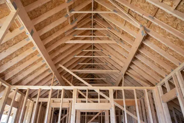 Wood roof framing interior showing rafters, ridge line, and wall framing carrying roof loads.