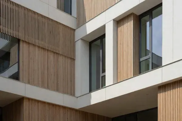Modern facade with vertical timber screens, deep window reveals, and light mineral cladding panels.