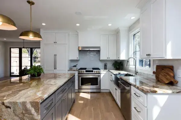 Close-up of white shaker kitchen cabinets meeting polished brown granite countertop with warm caramel and gold veining, brushed brass hardware.