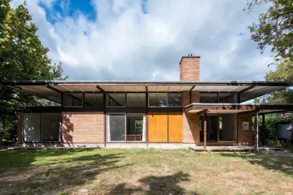 1960s ranch-style house with low roofline, brick, and wide front windows.
