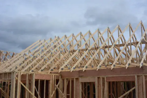 Wood-framed house under construction with prefabricated Fink roof trusses in place.