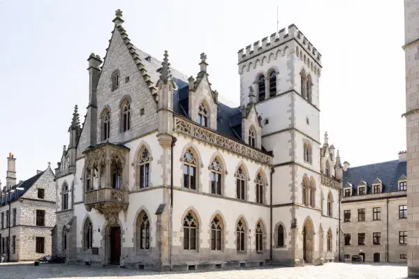 Gothic civic building with pointed windows, stone walls, and a tall tower.