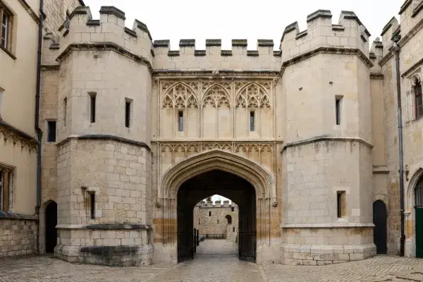 Gothic gatehouse with pointed arch entry, towered massing, and stone facade.