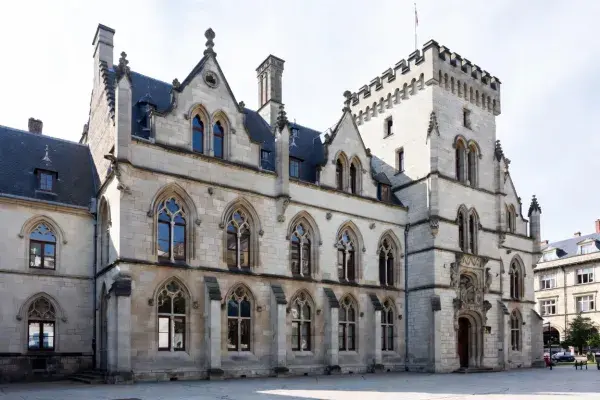 Gothic civic building with pointed arch windows, tower, and stone facade.