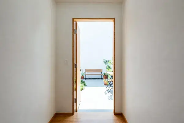 Narrow interior hall opening to a small patio with bench seating and a simple clear path.