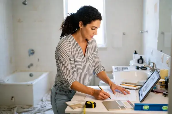 Homeowner reviewing bathroom renovation plans, measurements, and finish samples.