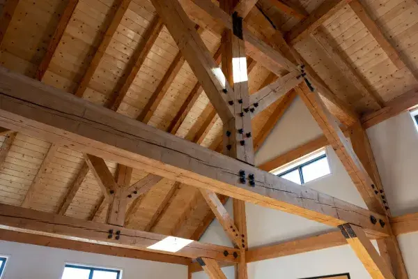 Exposed timber roof truss with heavy beams, braces, and visible steel connectors.