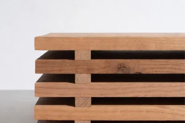 Wood boards stacked with spacer sticks to acclimate indoors.
