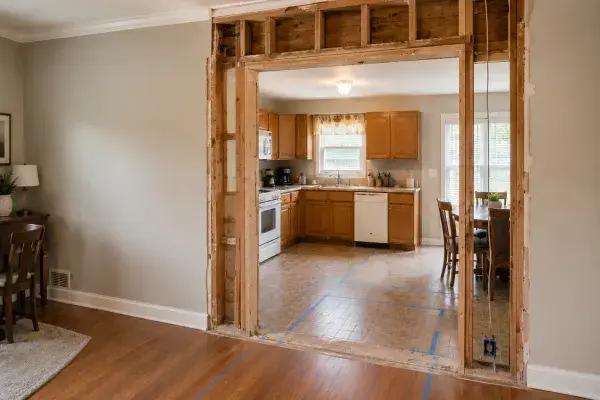 Opened wall above a ranch kitchen doorway showing exposed studs and inspection framing.