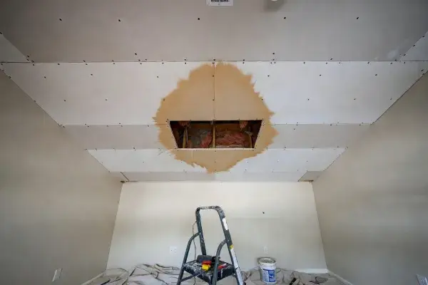 Wet ceiling drywall with a small cutout exposing the leak area above the damaged patch.