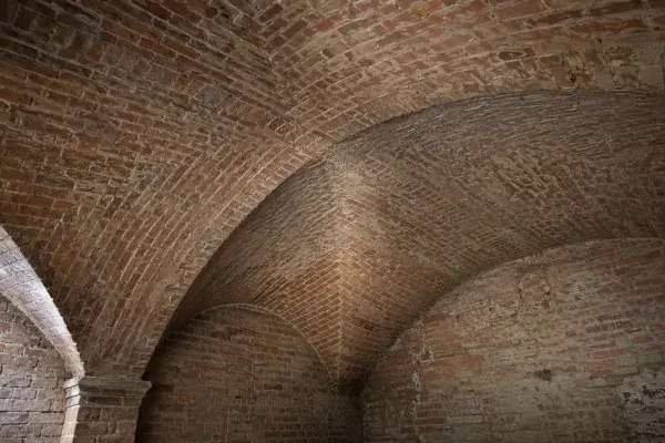 Close view of a brick groin vault showing the diagonal intersection of two curved vault surfaces.
