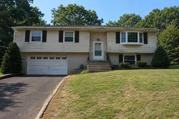 Dated raised ranch exterior with worn lawn, plain stairs, and weak front entry before remodeling.