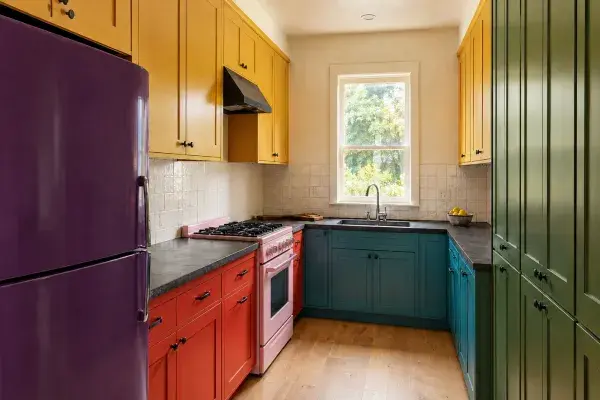 Color-blocked kitchen with red, teal, yellow and green cabinets.