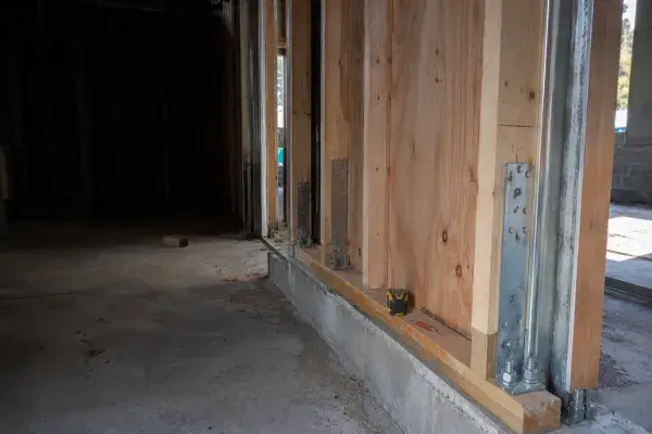 Seismic retrofit framing with plywood shear panels, hold-down anchors, and concrete foundation.